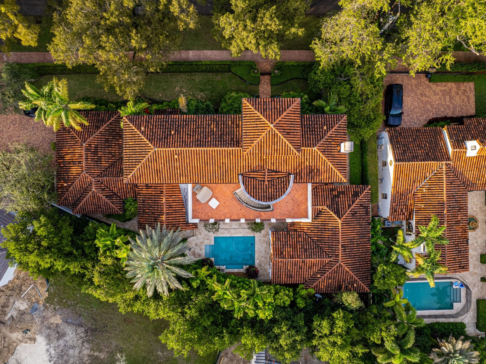 Aerial view of tile-roofed houses with swimming pools and palm trees